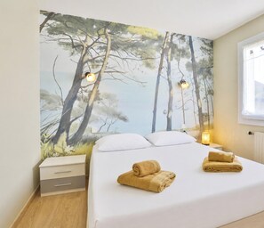 Ein Schlafzimmer mit einem Bett, zwei Nachttischen, einer Ablage und einer Wandmalerei von Bäumen.