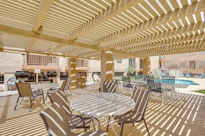 Eine Außenpatio mit überdachter Sitzgruppe, einem Pool und Grillanlagen.