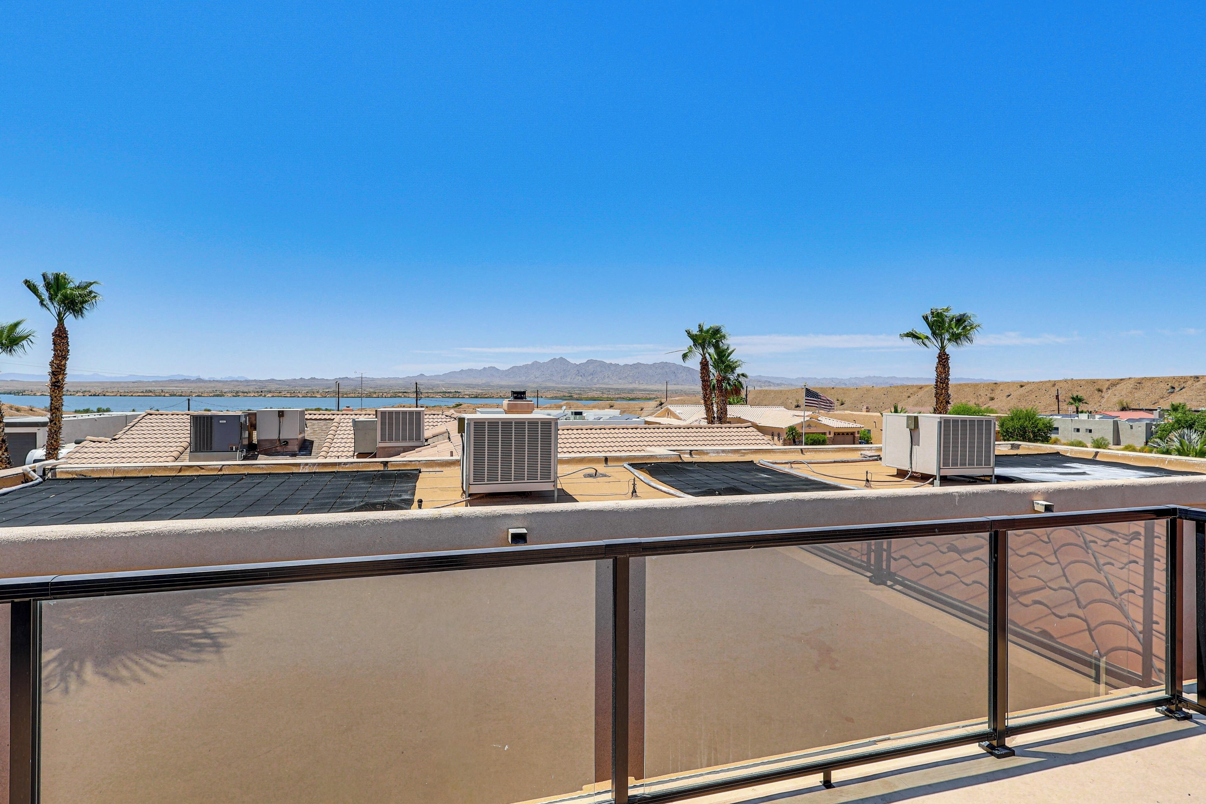 A rooftop terrace with solar panels, air conditioning units, and palm trees.