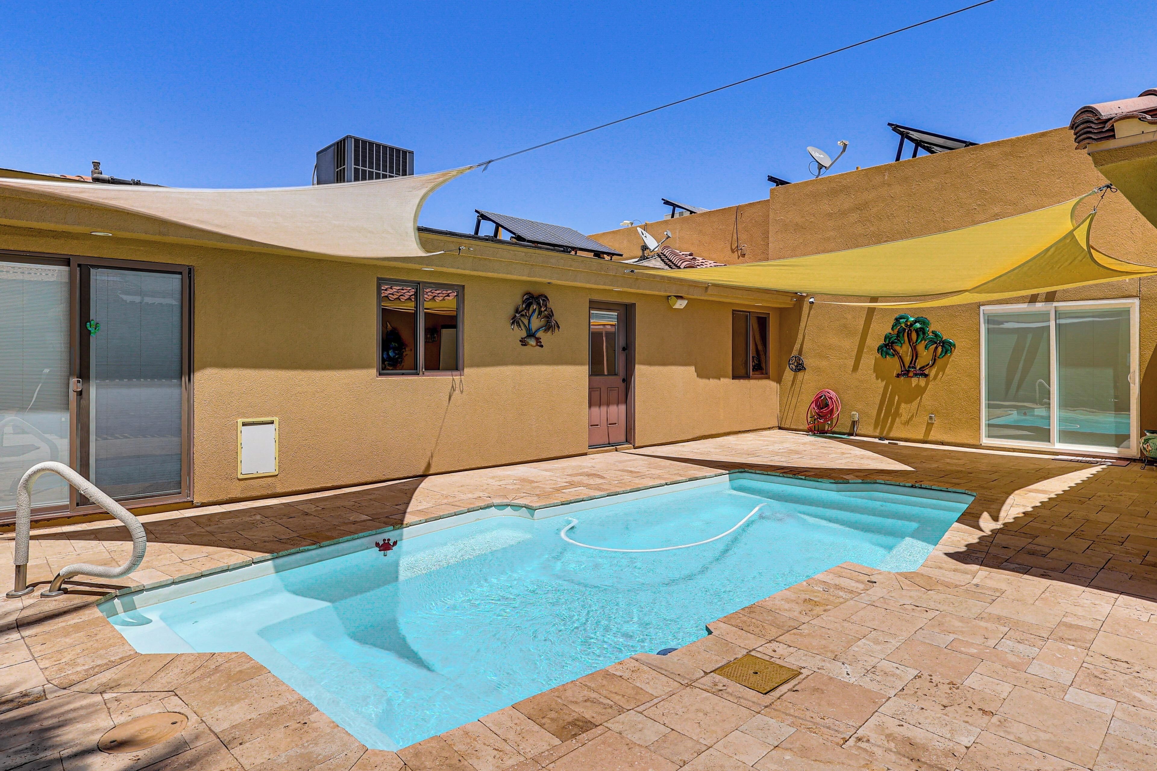 A swimming pool with a sunshade, a sliding glass door, and a satellite dish on the building.
