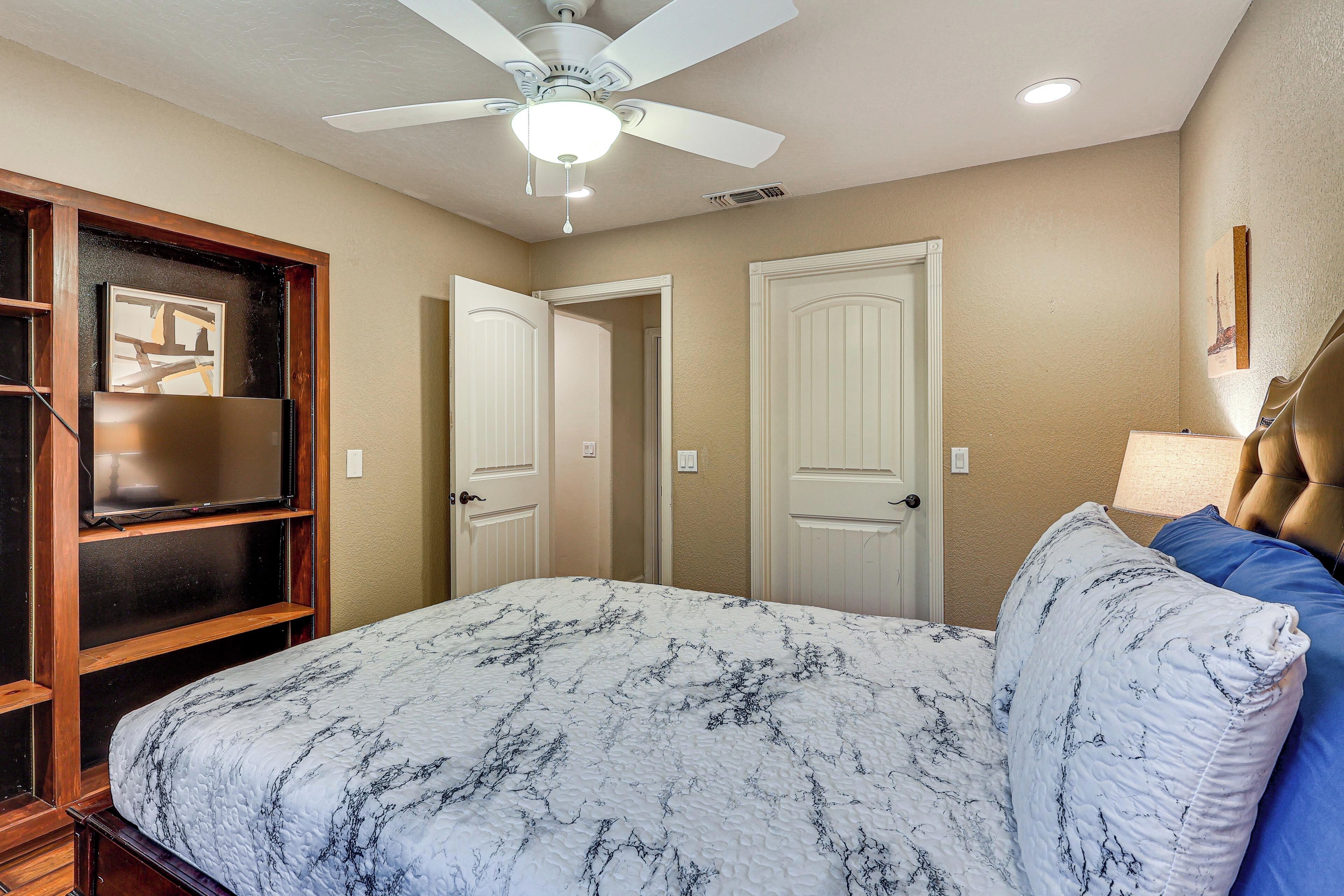 A bedroom with a bed, a ceiling fan, and two doors.