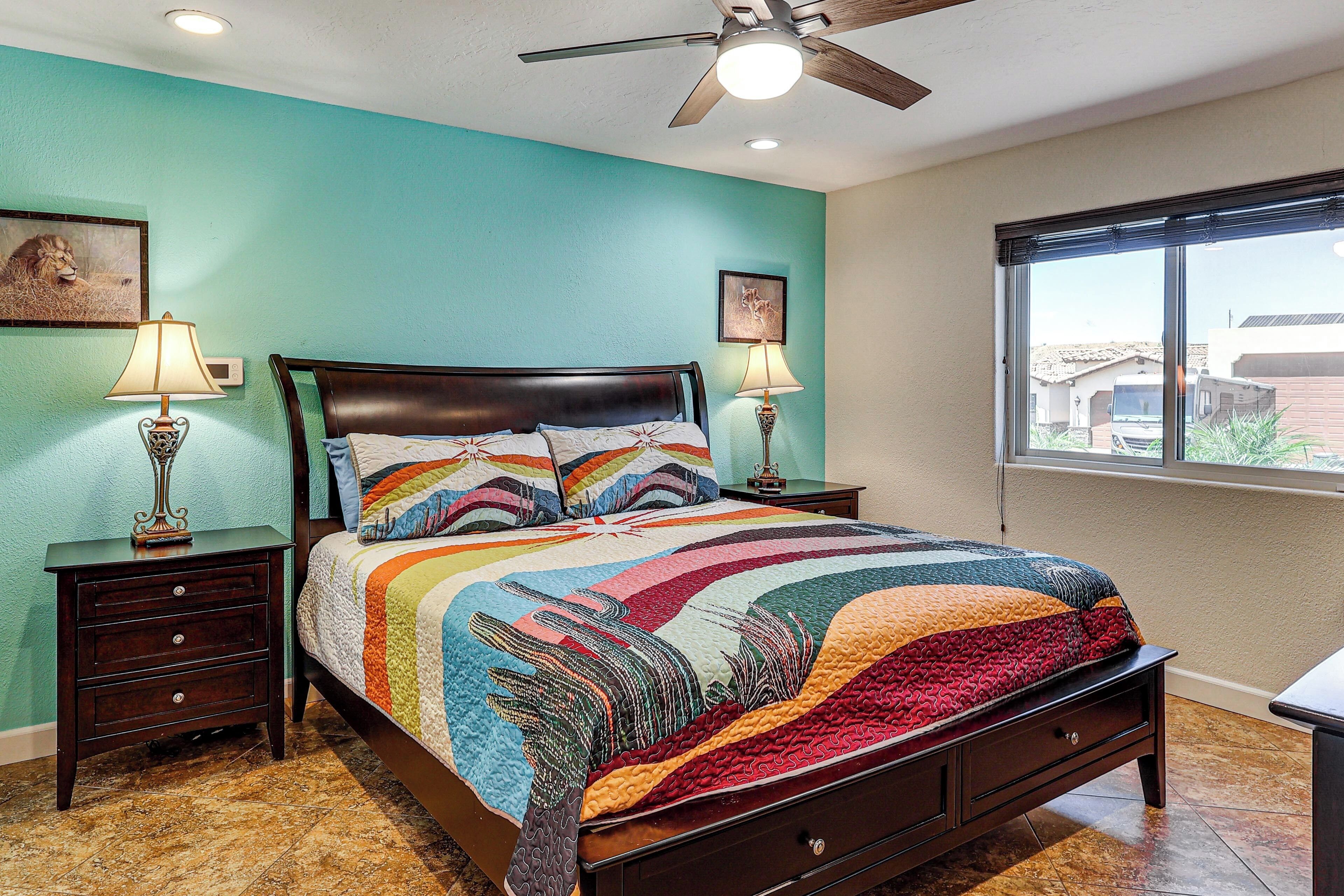 A bedroom with a bed, two nightstands, a ceiling fan, and a window.