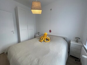 Ein Schlafzimmer mit einem Bett, einem Nachttisch, einer Lampe, einem Heizgerät und einem Spielzeug-Oktopus.