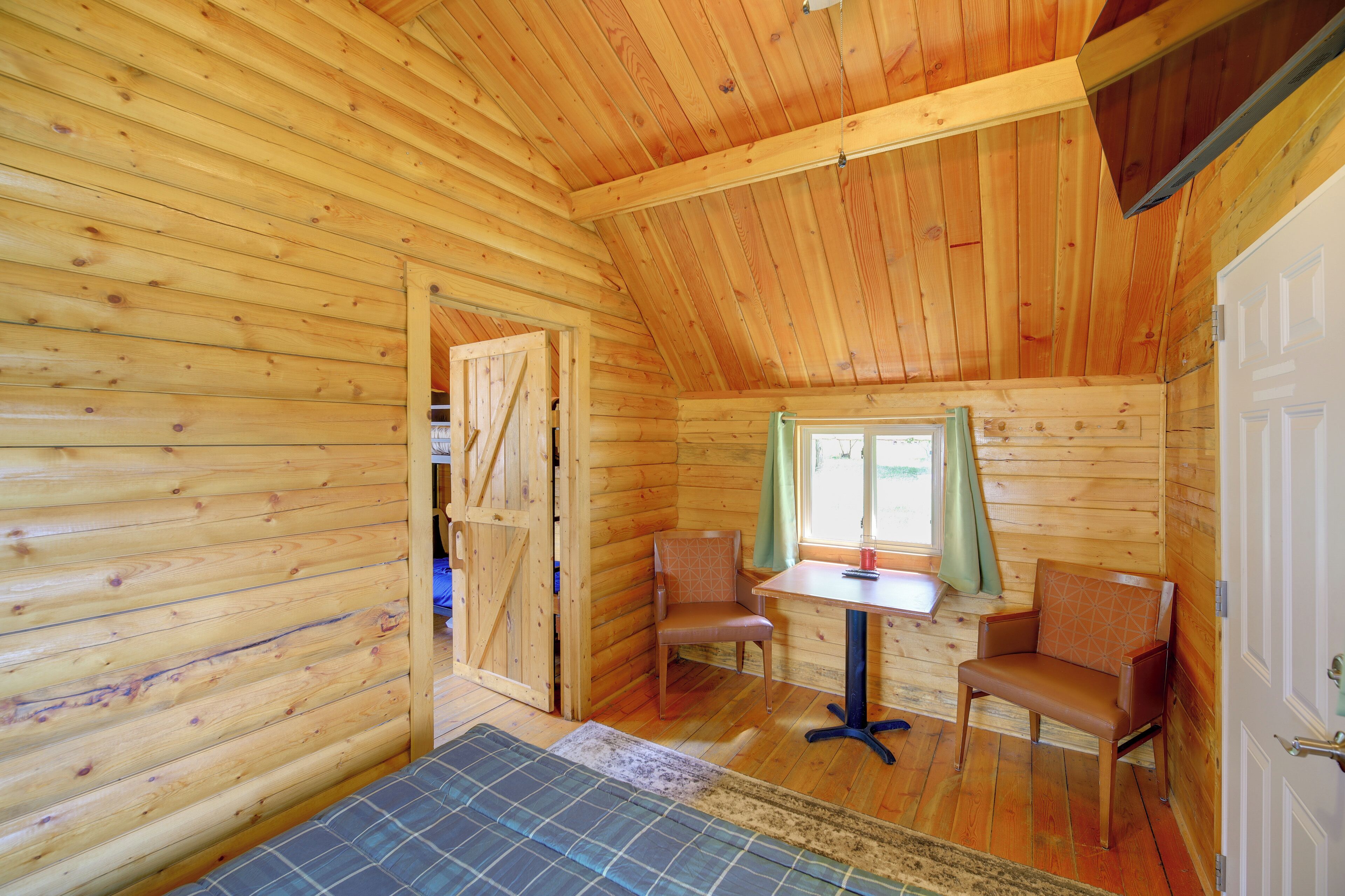 Ein Holzblockhaus-Interieur mit Essbereich, zwei Stühlen, einem Tisch und einer Tür.