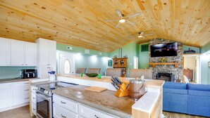 A kitchen with white cabinets, a large island, and a stone fireplace. - Lakefront Home and 2 Cabins on Claytor Lake (Hiwassee)
