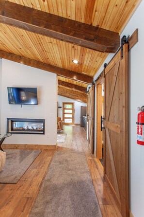 Ein Flur mit Holzboden, Kamin, Fernseher und einer Schiebetür im Bauernhausstil.