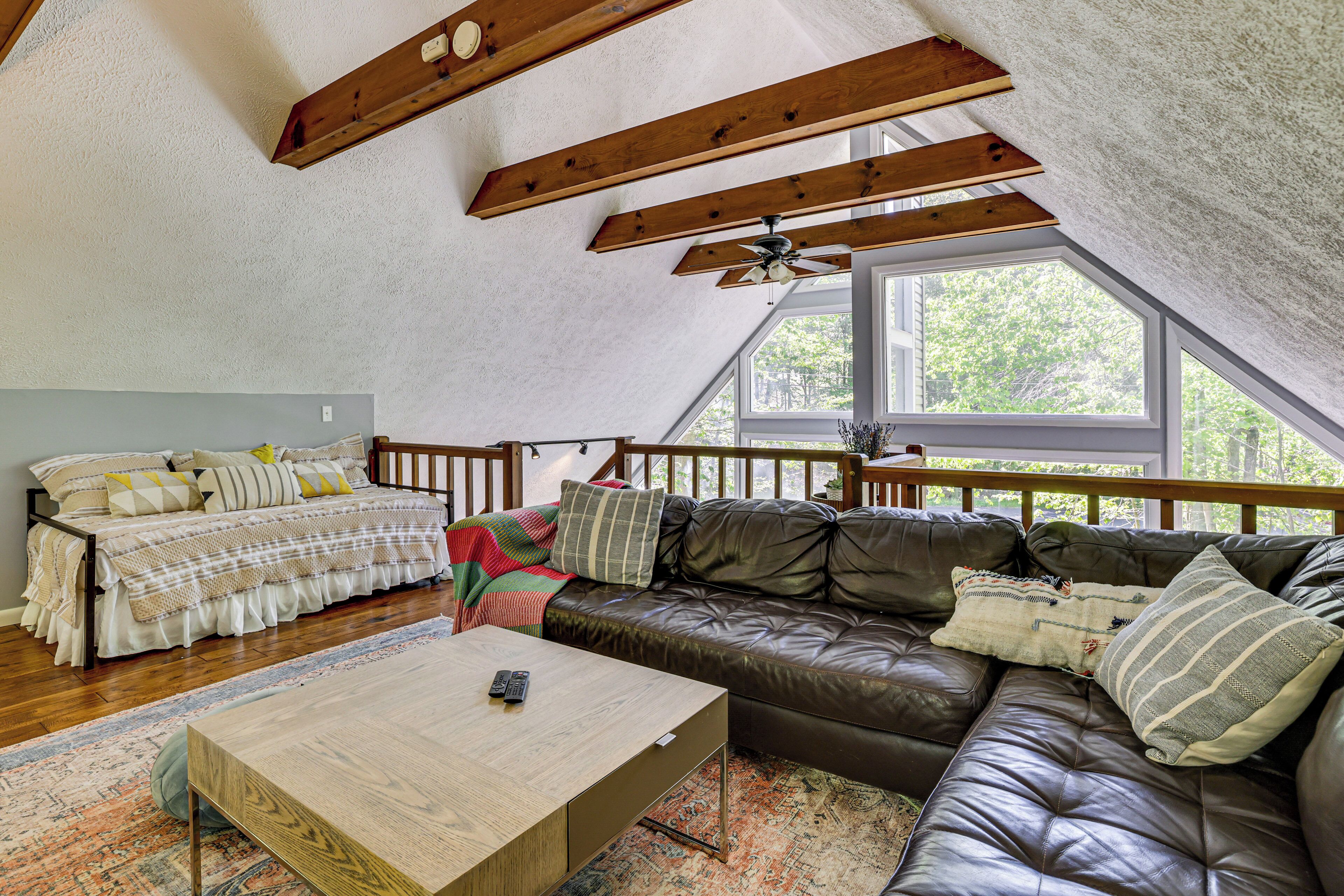 A loft-style room with a loft bed, a leather sofa, and a wooden coffee table.