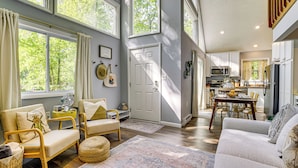 A spacious living room with large windows, a dining area, and a kitchen with modern appliances.