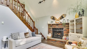 A living room with a fireplace, a staircase, a sofa, and a bookshelf.