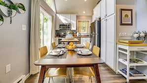 A modern kitchen with white cabinets, a dining table set for six, and a kitchen island with a microwave.
