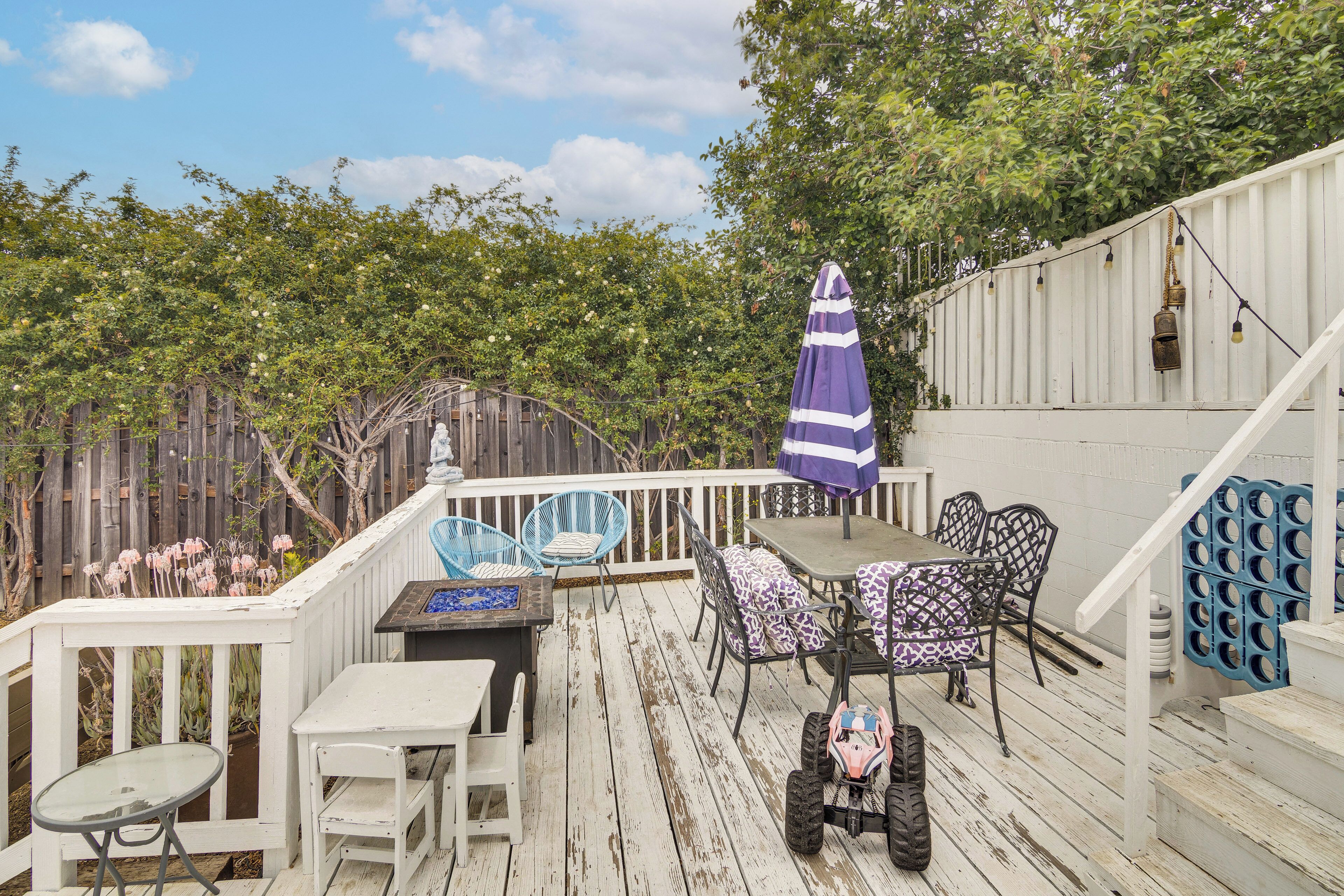 A wooden deck with outdoor furniture, including a table and chairs, and a small children's ride-on toy.