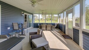 A covered porch with wicker furniture, ceiling fans, and large windows offering a view of the outdoors. - Peaceful Lake Escape w/ Dock in Coffee County (Douglas)