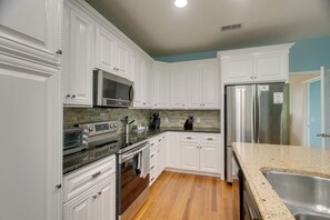 A kitchen with white cabinetry, stainless steel appliances, granite countertops, and a wooden floor. - Peaceful Lake Escape w/ Dock in Coffee County (Douglas)