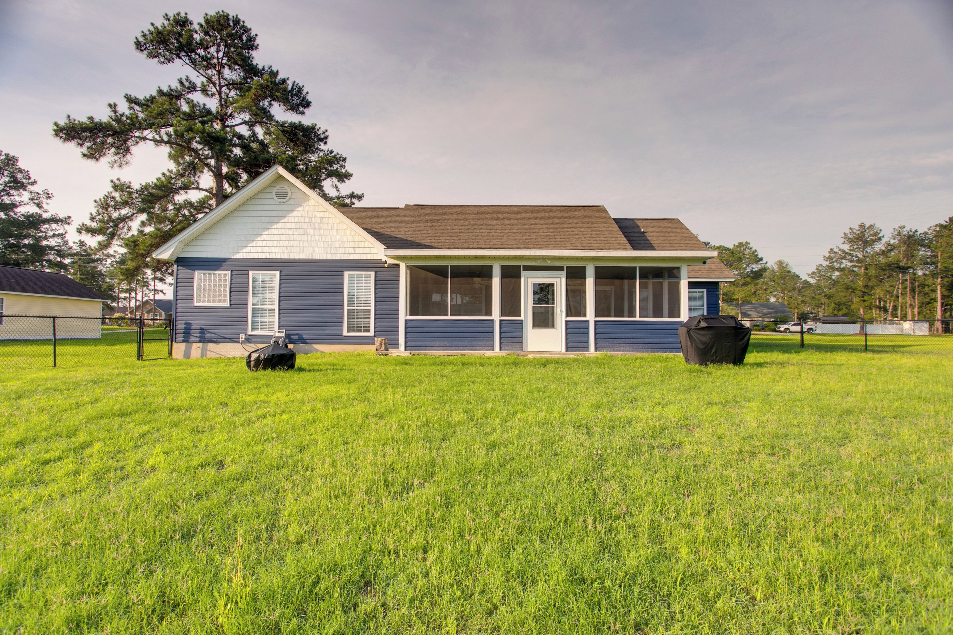 A single-story house with a porch, a lawn, and a large tree.