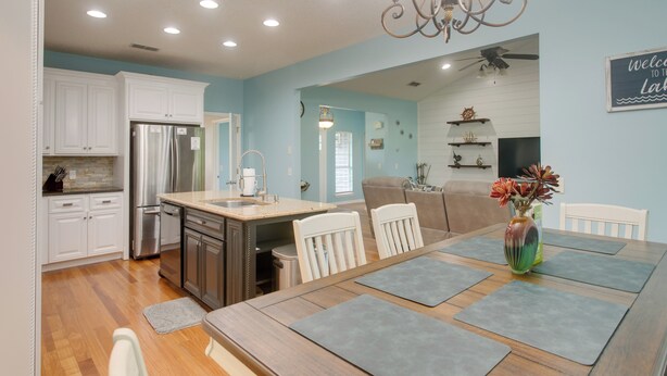 A modern kitchen with white cabinets, a stainless steel refrigerator, and a dining area with a wooden table and chairs. - Peaceful Lake Escape w/ Dock in Coffee County (Douglas)