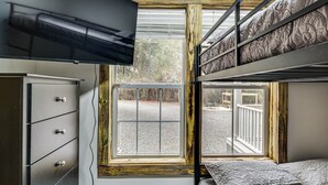 A bunk bed room with a TV mounted above the bed, a dresser, and a window with a view of the outside. - Group-friendly Escape! Gateway to Gulfport Beaches (Gulfport)