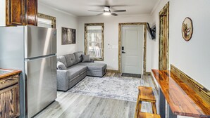 A compact kitchen with a stainless steel refrigerator, a gray sectional sofa, and a wooden dining table. - Group-friendly Escape! Gateway to Gulfport Beaches (Gulfport)