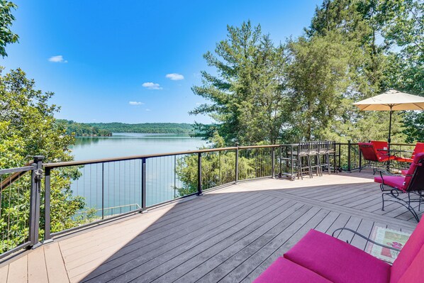 A deck with a view of a lake, outdoor furniture, and a railing.