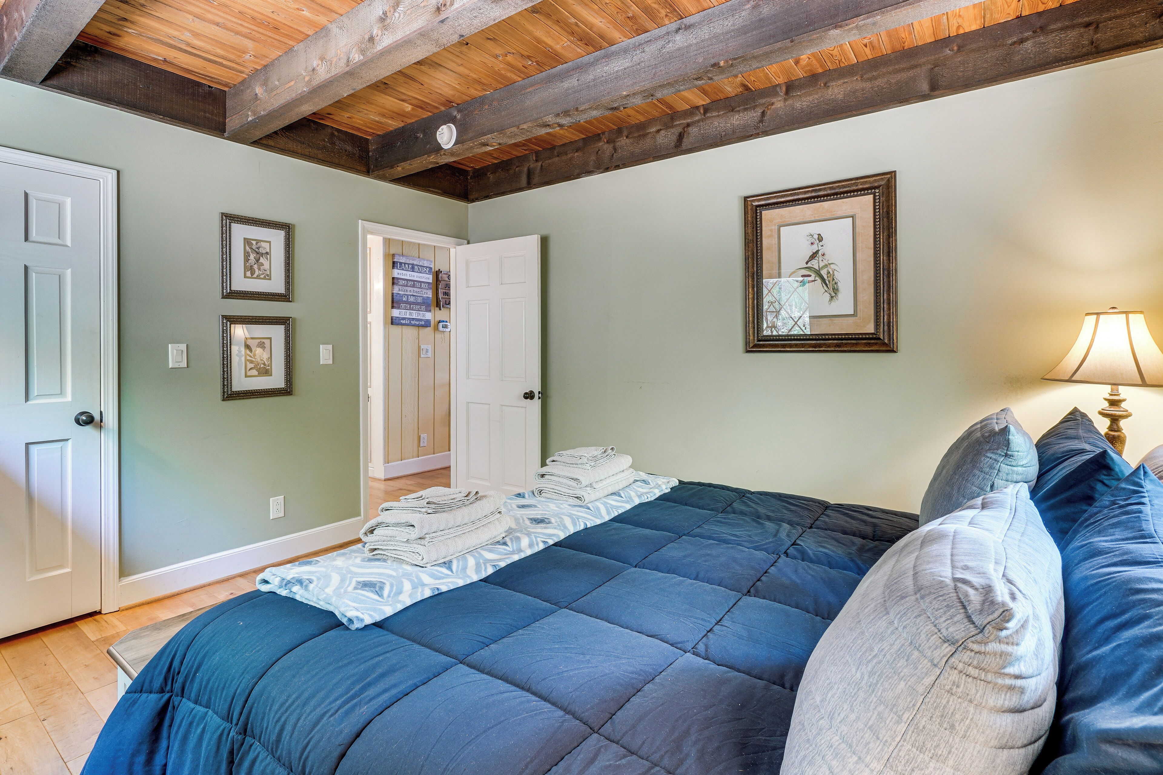 A bedroom with a bed, a door, and framed pictures on the wall.