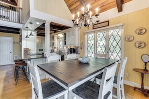 A spacious kitchen with a large island, white cabinetry, and a chandelier.