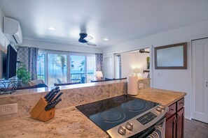 A kitchen with a large island, a stove, and a ceiling fan. - Beachfront with air conditioning, great walkable and central Kapaa location (Kapaa)