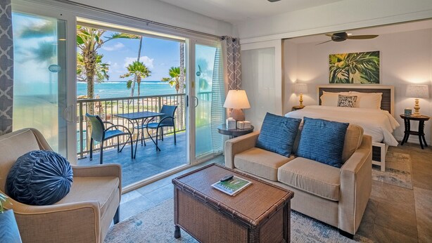 Ein Hotelzimmer mit Balkon, Bett, Sofa, Couchtisch und Meerblick.