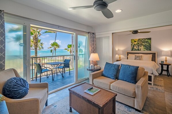 A hotel room with a balcony, a bed, a sofa, a coffee table, and a view of the ocean. - Beachfront with air conditioning, great walkable and central Kapaa location (Kapaa)