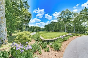A golf course with a stone wall, manicured lawn, and purple flowers. - Amazing Mtn Views at 'fore Seasons' in Trillium (Cashiers)