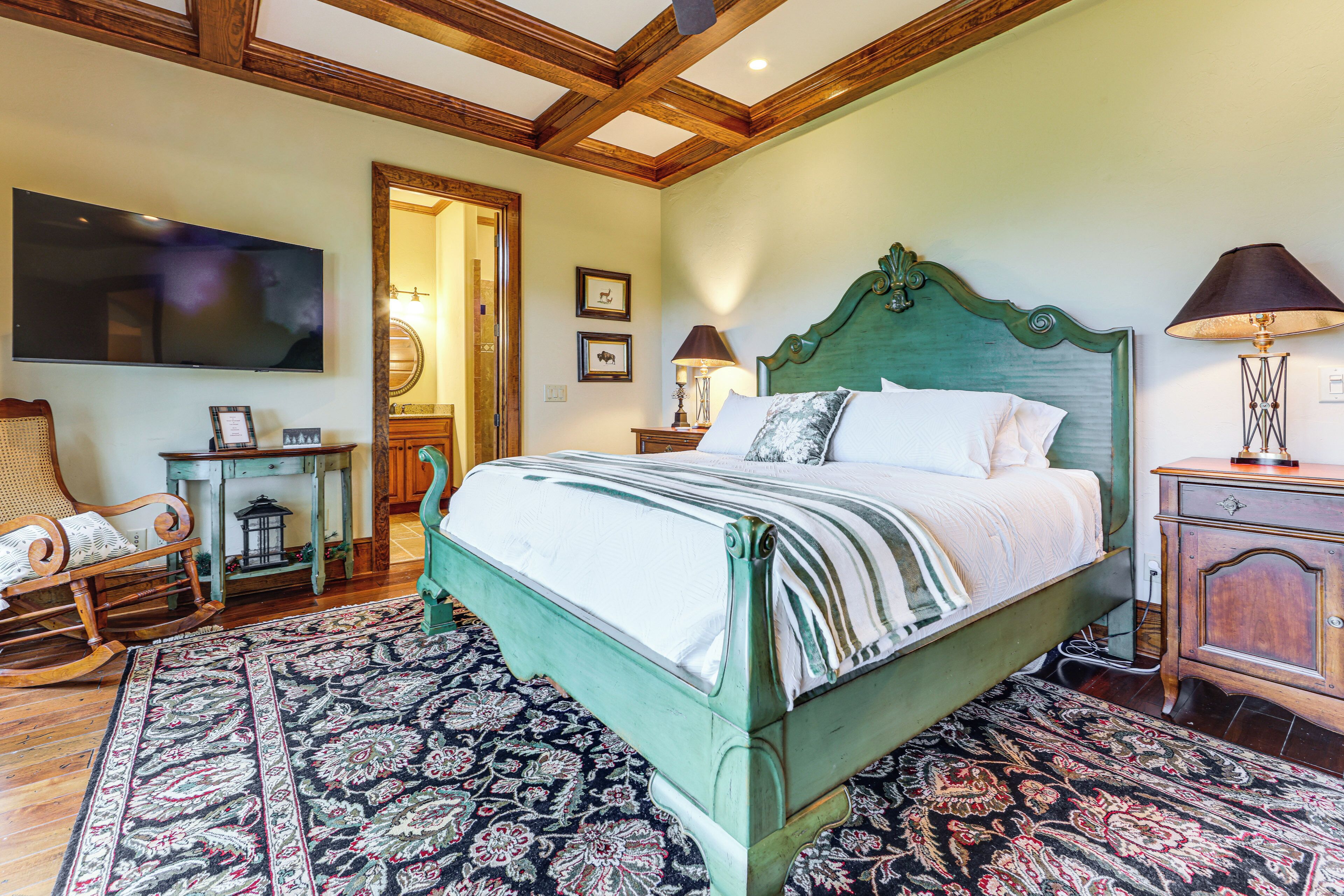A bedroom with a bed, a television, a wooden rocking chair, a small table, and a nightstand.