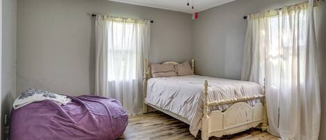 A bedroom with a bed, a ceiling fan, and a bean bag chair.
