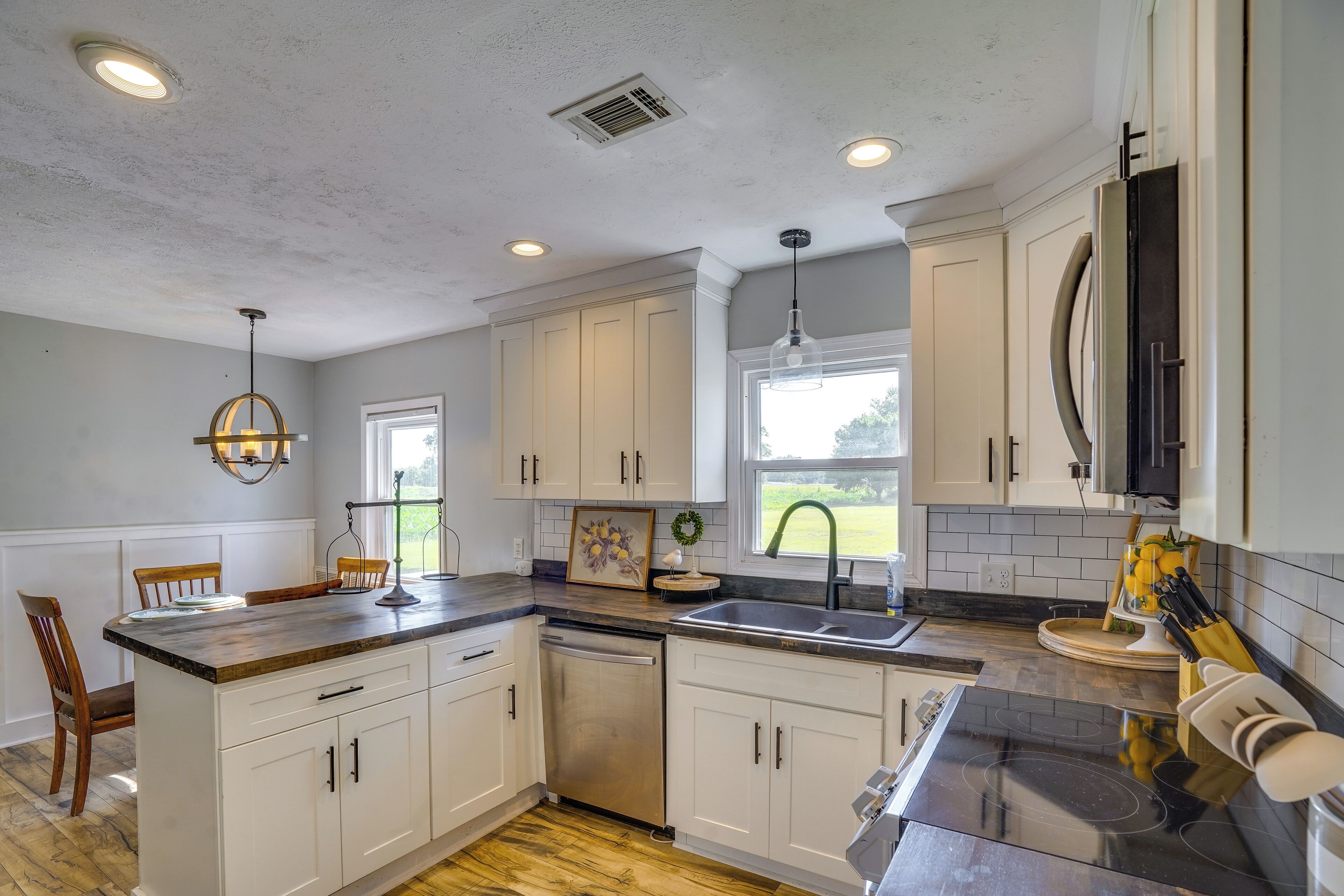 A kitchen with white cabinets, a black countertop, and a dishwasher.