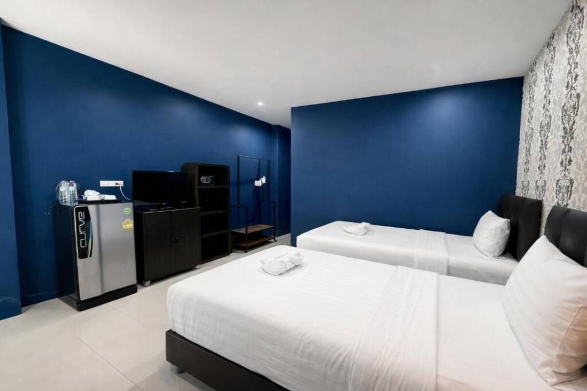 A hotel room with two beds, a minibar, a TV, and a mirror.