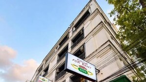 A building with a sign for a room for rent, outdoor seating with umbrellas, and potted plants. - Central Perk Patong (Patong)