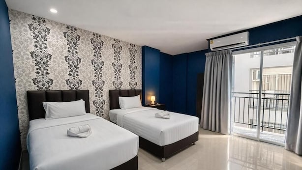 A hotel room with two beds, a large window with curtains, and an air conditioning unit. - Central Perk Patong (Patong)