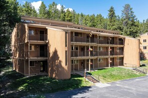 A multi-story wooden building with balconies, a covered entrance, and a grassy area in front. - Newly renovated 1 bedroom, ground floor, extra amenities (Winter Park)