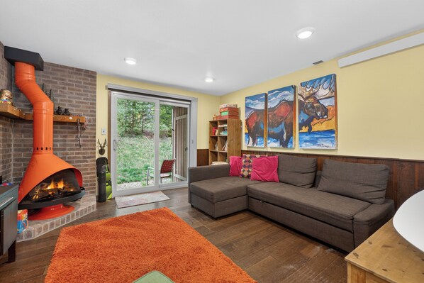 A living room with a fireplace, a sofa, a rug, and artwork on the wall. - Newly renovated 1 bedroom, ground floor, extra amenities (Winter Park)