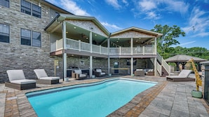 A swimming pool with lounge chairs, a covered patio, and a stone exterior. - Pool, Hot Tub + Views: Spacious Danville Escape! (Danville)