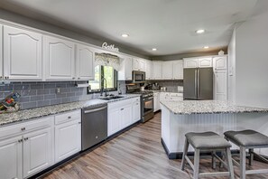 A modern kitchen with white cabinetry, granite countertops, stainless steel appliances, and a central island with bar stools. - Pool, Hot Tub + Views: Spacious Danville Escape! (Danville)