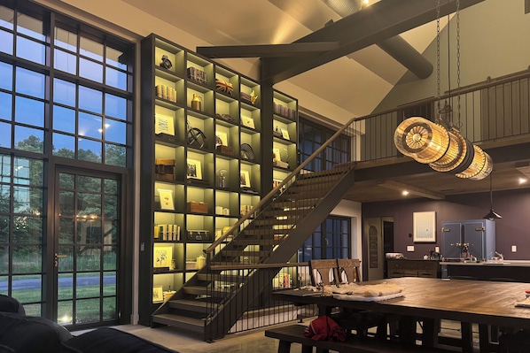 Un interior espacioso con una amplia escalera, un comedor y una estantería bien iluminada.