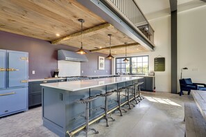 A modern kitchen with a large island, bar stools, and a staircase leading to an upper level.