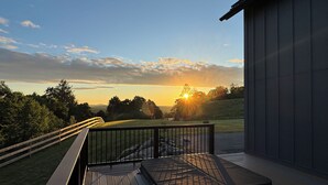 Een terras met uitzicht op de zonsondergang boven een grasrijk landschap.