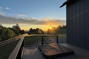 Une terrasse offrant une vue sur le coucher de soleil au-dessus d’un paysage verdoyant.