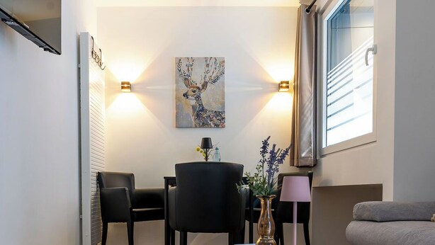 A modern living room with a wooden floor, a black sofa, a grey armchair, a black table with a tray, and a painting on the wall. - Vacation apartment 1 - Gasthaus Bußmann (Vreden)