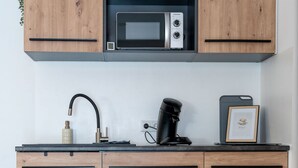 A kitchen with wooden cabinets, a microwave, a coffee maker, and a framed picture on the counter. - Vacation apartment 1 - Gasthaus Bußmann (Vreden)