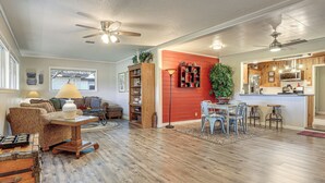 A spacious living area with a dining table, sofas, and a kitchen area with wooden cabinets and a red accent wall. - Walk to Shops & Eats! Family Escape in Columbus (Columbus)