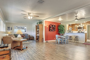 A spacious living area with a dining table, sofas, and a kitchen area with wooden cabinets and a red accent wall. - Walk to Shops & Eats! Family Escape in Columbus (Columbus)