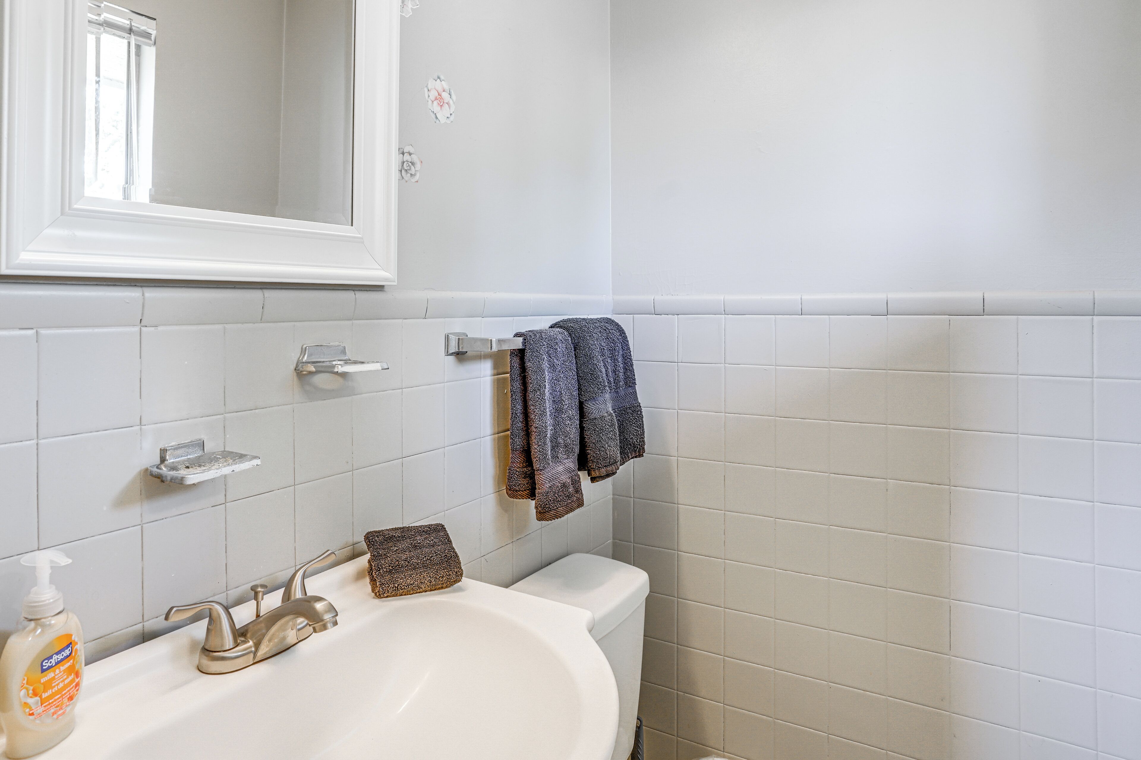 A bathroom with a white sink, a mirror, a towel rack, and a toilet.
