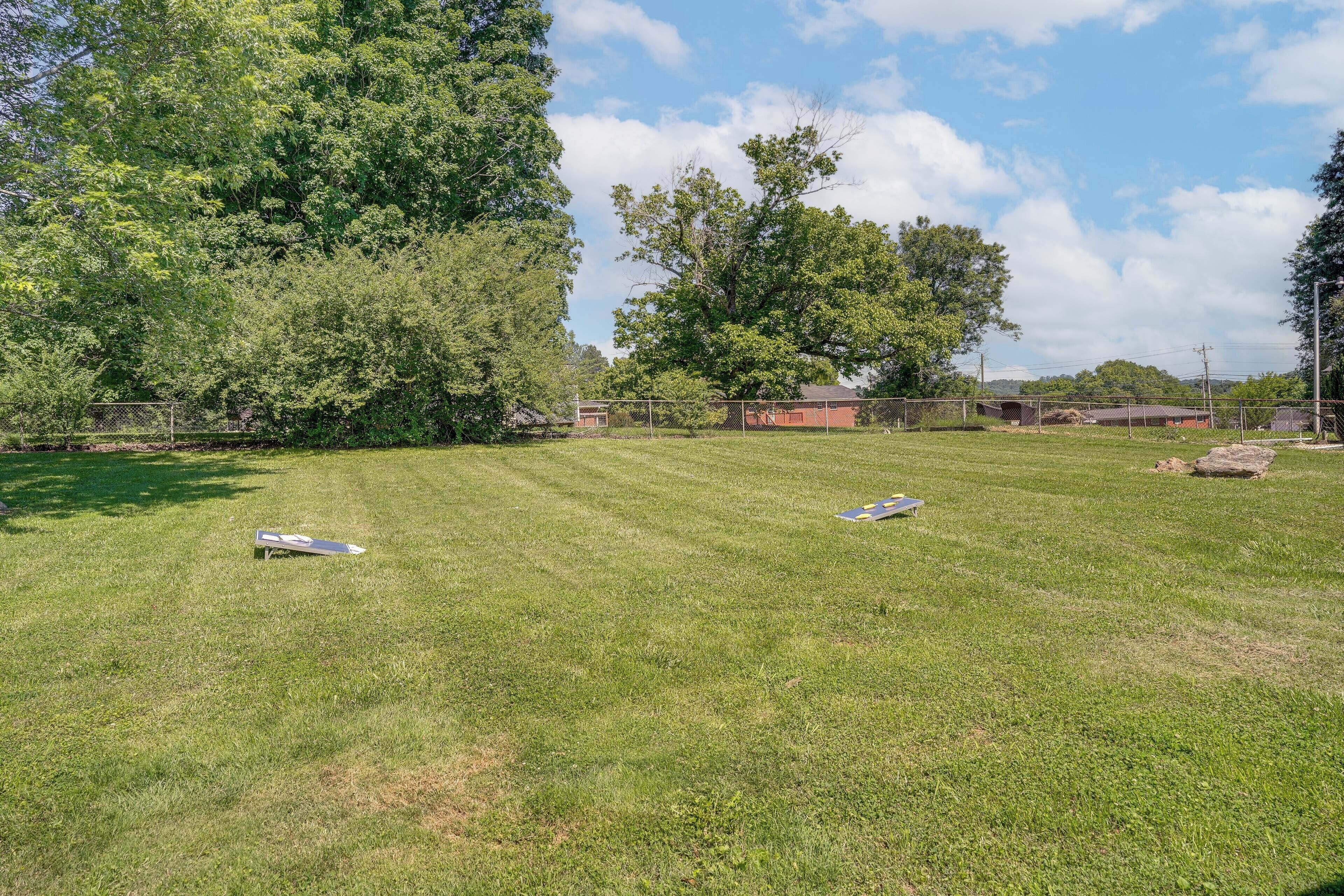 A grassy outdoor area with trees and a fence.