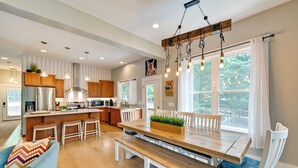 A modern kitchen with wooden cabinets, a central island, and pendant lighting. - Lakehouse Blue: Fire Pit, Hot Tub on Lake Norman! (Sherrills Ford)