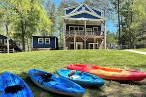 A two-story building with a balcony, surrounded by trees and a grassy lawn. - Lakehouse Blue: Fire Pit, Hot Tub on Lake Norman! (Sherrills Ford)